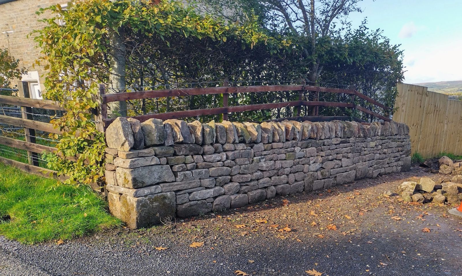 Rebuilt dry stone boundary wall running alongside a farm track.